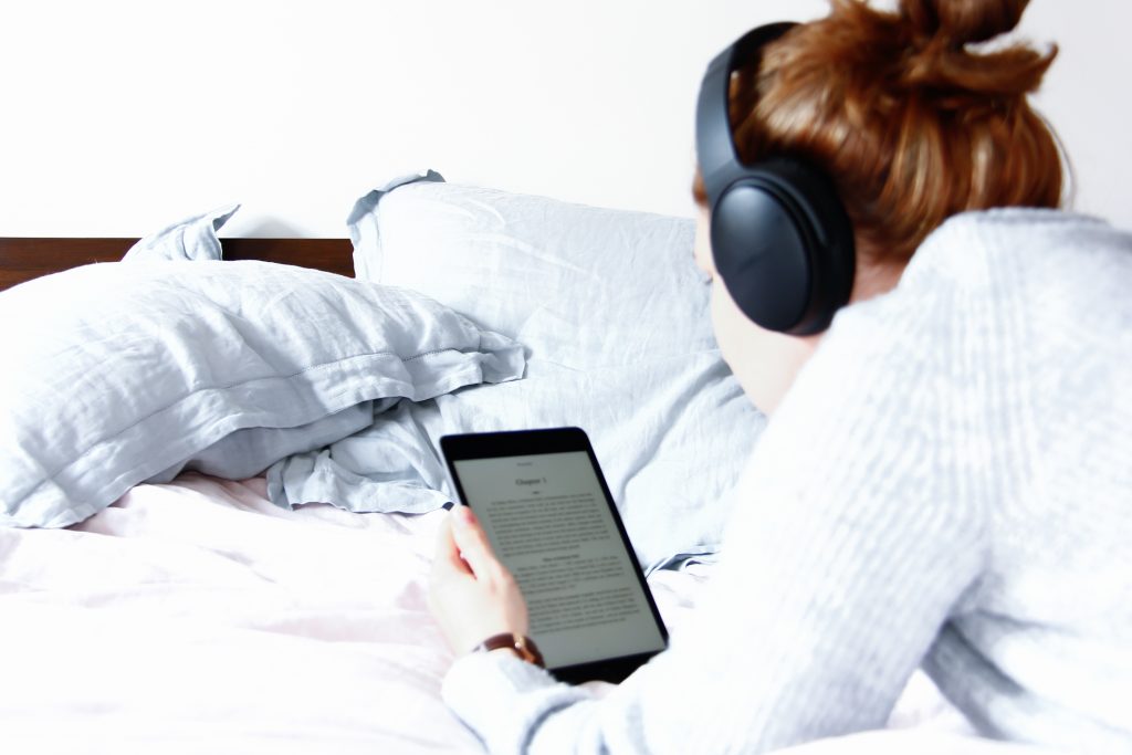 woman in headphones reading a digital book in kindle